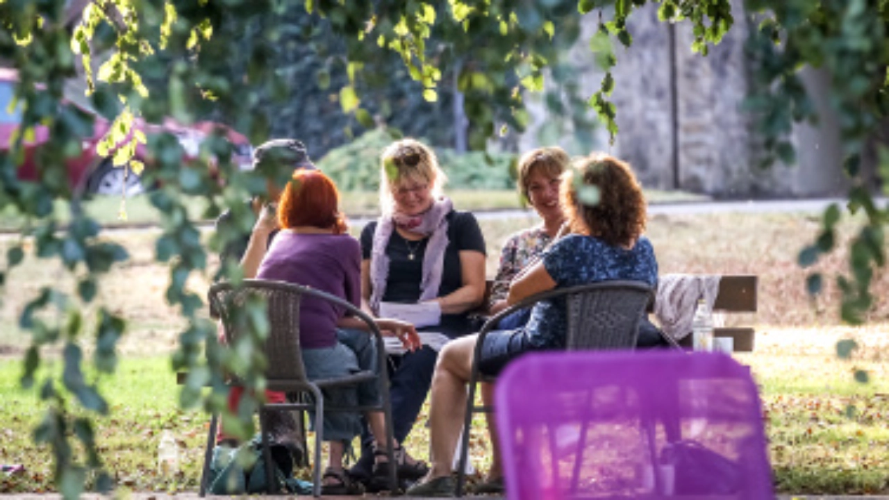 Frauen sitzen draussen und unterhalten sich.