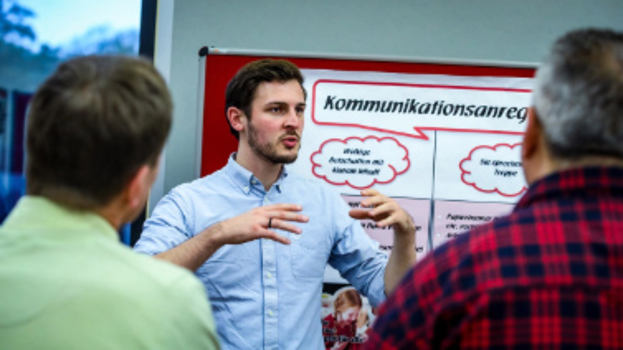 Ein junger Mann spricht vor einer Seminargruppe.