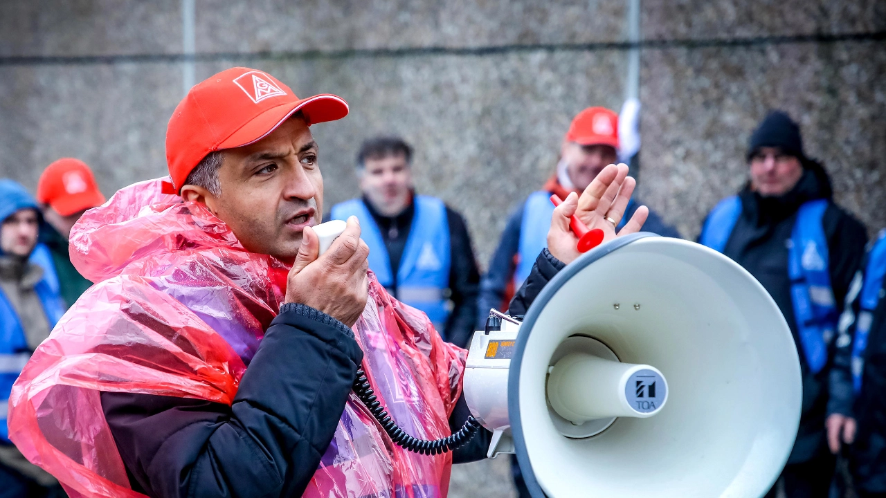 Metaller mit roter IG Metall-Kappe, Regencape und Lautsprecher.