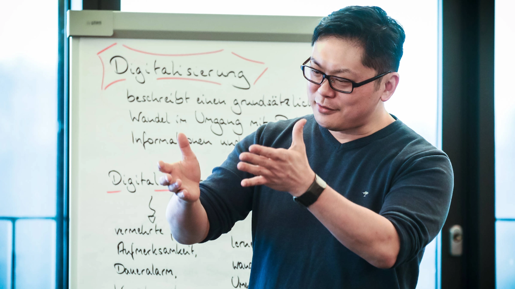Ein junger Mann steht gestikulierend vor einer Metaplanwand.
